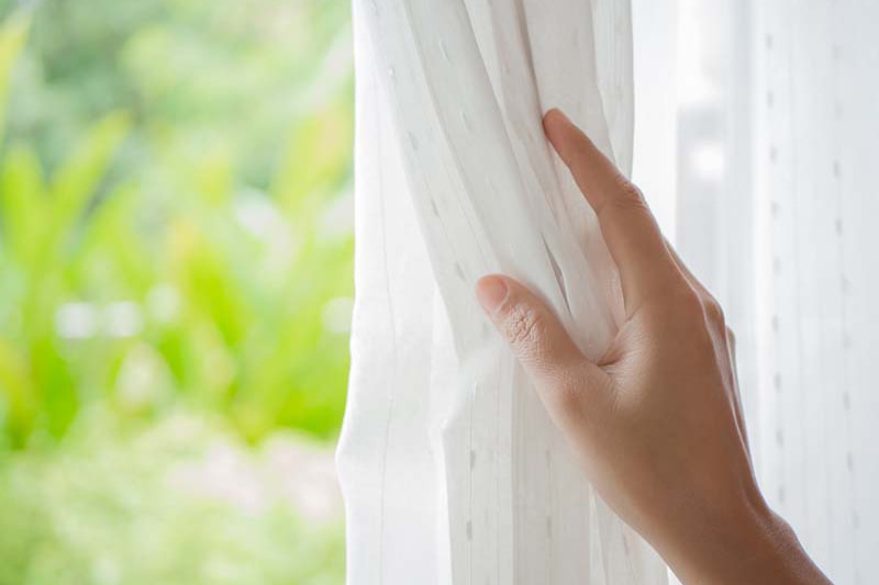 woman's hand on curtain