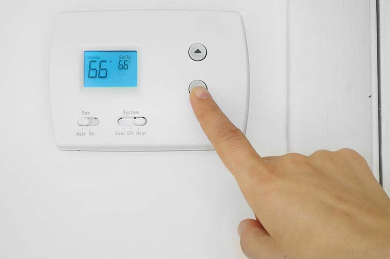 hand controlling white thermostat
