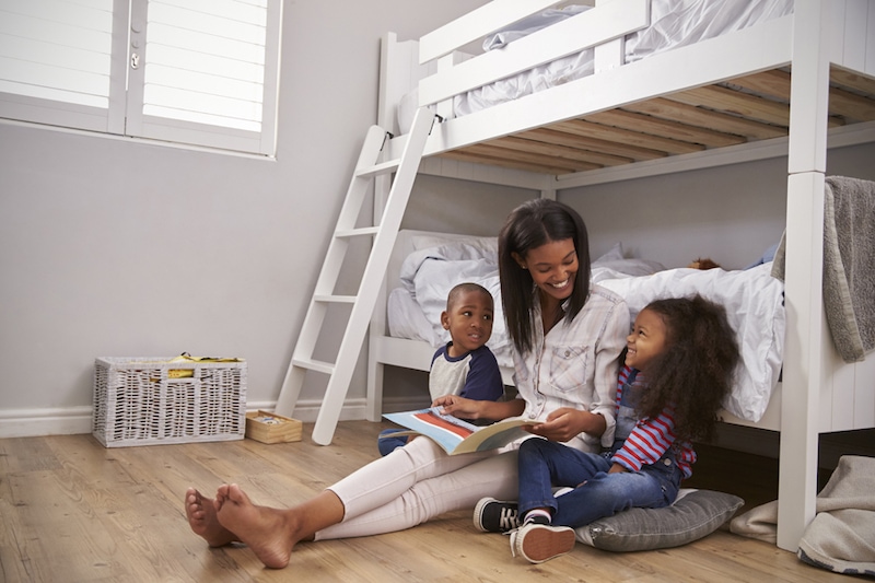 Mother Reading Story To Children In Their Bedroom