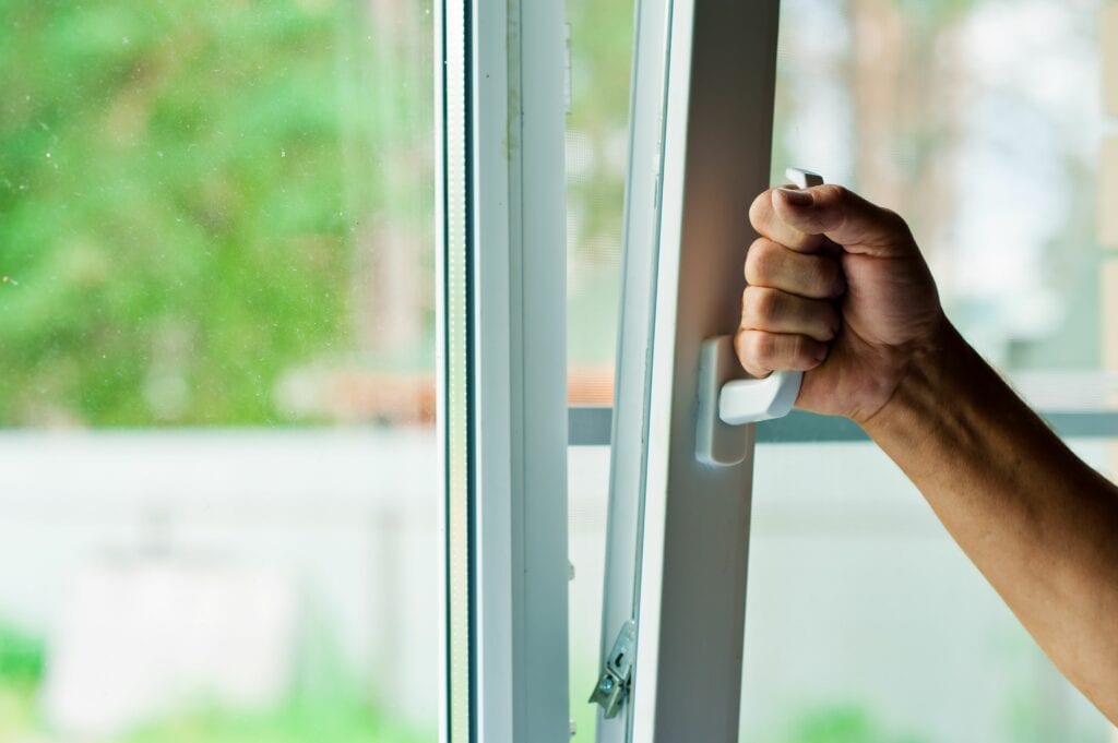 How Environmental Issues Can Affect Your AC. Image depicts person opening window.